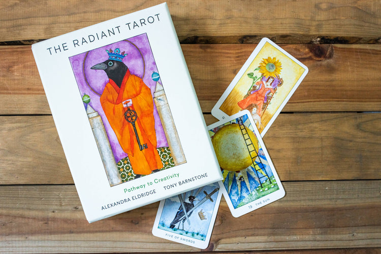 Radiant Tarot deck box and cards with vibrant illustrations on wood background