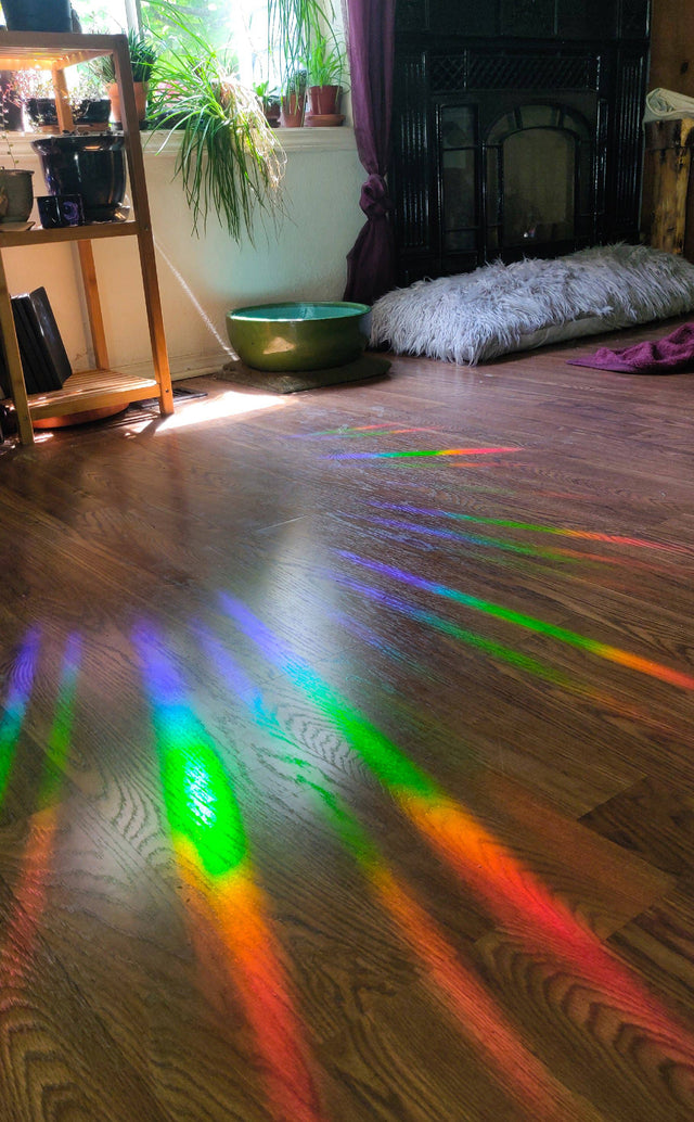 Rainbows from the Baba Yaga suncatcher decal scattered across a wood floor