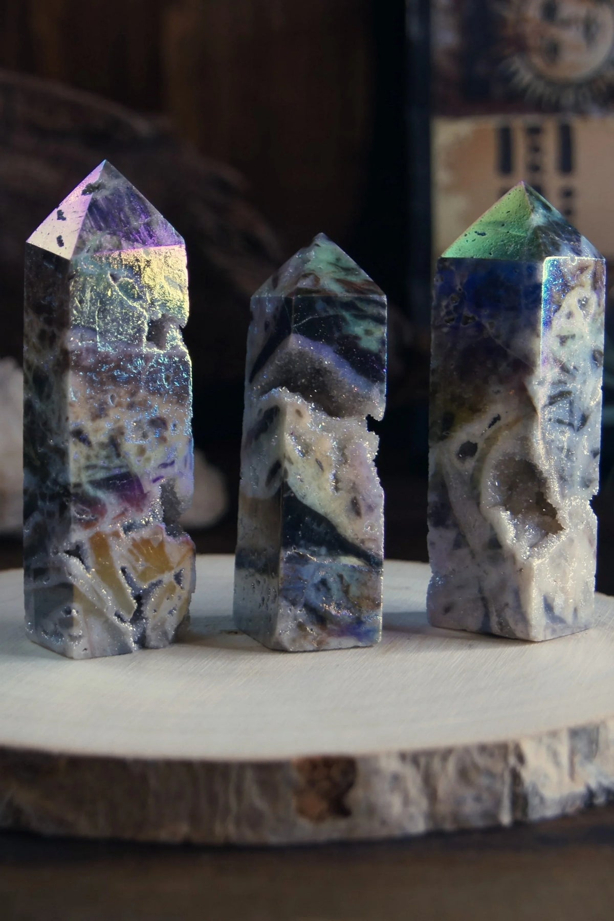 Three polished crystal towers with colorful, natural patterns on a wood slice display