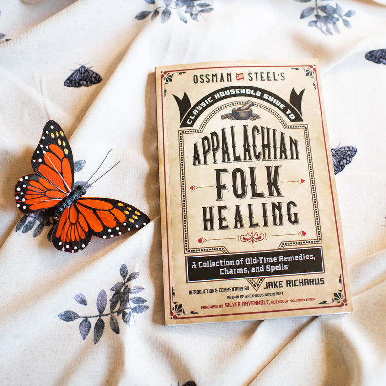 Appalachian folk healing book on floral cloth with a decorative orange butterfly
