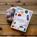 The Little Book of Crystals and a purple crystal cluster on wooden background