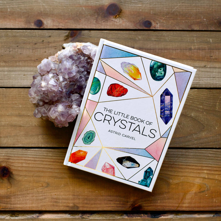 The Little Book of Crystals and a purple crystal cluster on wooden background