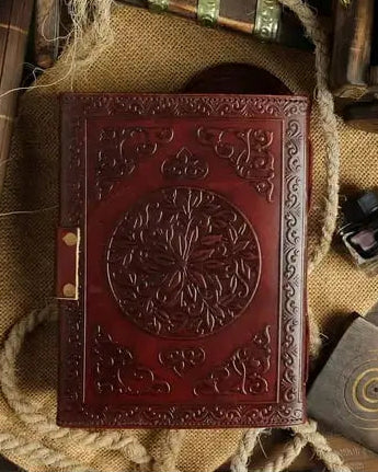 Embossed leather journal with tree of life design, surrounded by tarot, crystals, and ritual tools for spiritual practice.