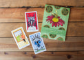 The Radiant Tarot guidebook and three tarot cards on a wooden table.