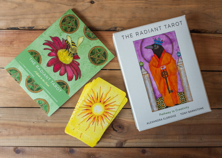 Radiant Tarot deck with illustrated cards, guidebook, and box on a wooden table.