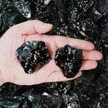 Hand holding two raw snowflake obsidian crystals with black and white patterns