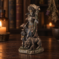 A detailed gothic figurine of a crowned woman with a snake draped over her shoulder, standing atop a wolf on a base labeled 'HELL', set on a wooden table with a blurred background of candles and books.