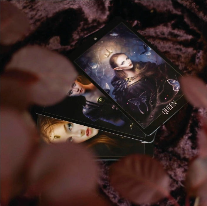 Stack of artistic tarot cards with ethereal queen illustration on velvet background