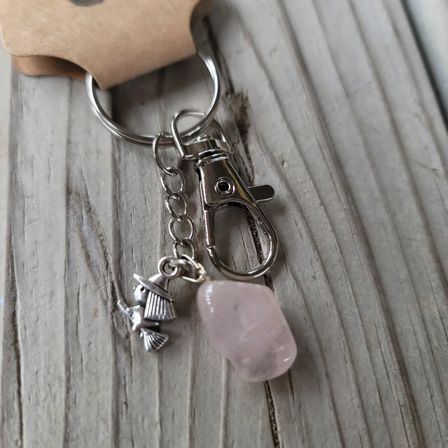 Rose quartz keychain with silver witch charm on rustic wood background